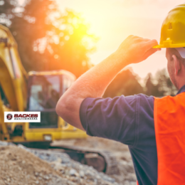 Image for Man with hard hat and orange vest looking on to construction equipment